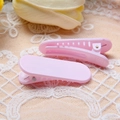 Gros plan de deux barrettes roses style macaron avec dents sur fond de dentelle blanche - Rose