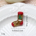 Vue macro d'une breloque botte de Noël pailletée dorée avec détails de sapins verts - Chaussette de Noël Dorée
