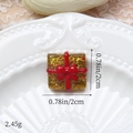 Vue macro de breloque cadeau pailletée or de 2cm avec nœud rouge sur fond de dentelle - Cadeau Doré