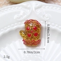 Gros plan d'une breloque gant de Noël en résine jaune avec des paillettes dorées - Moufles Ondulées Dorées