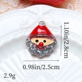 Vue macro des breloques Père Noël en résine avec barbe à paillettes argentées pour DIY - Visage de Père Noël à Paillettes Argentées