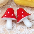 Gros plan de deux pendentifs champignons en résine rouge avec points blancs et anneaux - Rouge