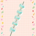 Detailed macro of acrylic Christmas beads with blue Cake lettering and white dots - White With Cake