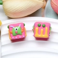 Macro shot of pink resin cube beads with 3D cartoon monster patterns for DIY crafts - One-eyed Monster / Rose Red