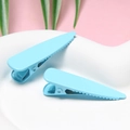 Detailed macro view of two sky blue matte finish metal teardrop duckbill hair clips - Blue