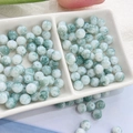 Macro detail of 8mm green and white marble textured glass beads in a ceramic tray - 100pcs Pack / Ink Wash - Morandi Green
