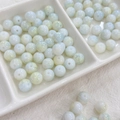 Detail of 8mm ink-style glass beads with blue crackle patterns in a ceramic tray - 100pcs Pack / Ink Wash - Blue Green Mixed