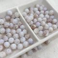 Macro detail of 8mm ink style glass beads with purple vein texture in a ceramic tray - 100pcs Pack / Ink Wash - Chestnut Brown