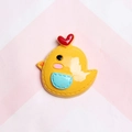 Macro view of a yellow resin chick charm with red heart detail for DIY craft decoration - Orange