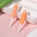 Detail von zwei orange-weißen Lutscher-Anhängern auf Steindisplay vor rosa Hintergrund - Orange