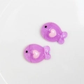 Macro shot of two purple glitter fish resin charms with pink hearts for DIY jewelry making - Purple