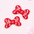 Close-up of red and white polka dot resin bow charms for DIY crafts and hair accessories - Polka Dot Bow / Red