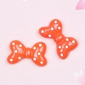 Primer plano de dos lazos de resina naranja con lunares para accesorios de pelo DIY - Lazo de Lunares / Naranja