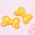 Macro detail of glossy yellow resin bow charms with white polka dots for DIY hair accessories - Polka Dot Bow / Bright Yellow