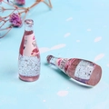 Macro detail of miniature peach chia seed drink bottles made of transparent resin - Pink