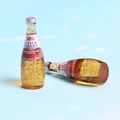 Detailed close-up of miniature pomegranate chia seed drink bottles for DIY jewelry making - Orange