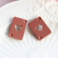 Détail macro de breloques poker en résine rouge avec découpe de cœur pour bijoux DIY - Marron