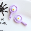 Detail of purple resin frying pan charms with egg design and integrated hanging loops - Light Purple
