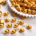 Makroaufnahme goldener Sycee-Miniaturen mit matter Textur auf einem weißen Teller - Gold
