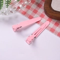 Close-up of pink matte metal alligator hair clips on a cozy home-style desktop - Pink