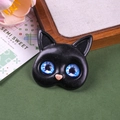 Detailed macro shot of a black resin cat accessory with vibrant blue galaxy glass eyes - Glacier Gem Eyes