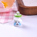 Macro view of a miniature resin milk bottle charm with cute expression and green neck ring - Green