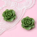 Detail von zwei grünen Harzrosen für DIY-Schmuckherstellung auf Spitzenhintergrund - Matcha-Grün