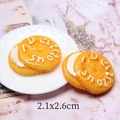 Macro-opname van 26mm gele hars koekjesbedeltjes met Delicious tekst en 2,1x2,6cm formaat - Crème Alfabet Koekje 21*26mm