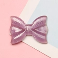 Close-up of a translucent purple resin bow with sparkling silver glitter for DIY crafts - 2.1x2.8cm / Purple Glitter