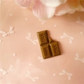 Gros plan d'un charme en résine chocolat avec texte MILK et détail de morsure - Grand / café