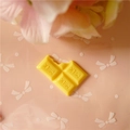 Vue macro d'un charme en résine chocolat jaune avec texte MILK et design de morsure - Grand / Jaune