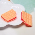 Macro detail of resin bite chocolate charm with pink filling in a white decorative dish - Sandwich Style-Pink