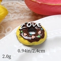Macro detail of a resin doughnut charm with chocolate coating and LOVE text on a plate - LOVE Coffee