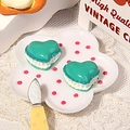 Macro detail of heart-shaped macaron resin charms on a small decorative ceramic dish - Blue Heart
