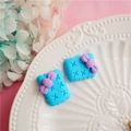 Macro shot of two blue bow biscuit clay accessories on a white embossed ceramic plate - Blue