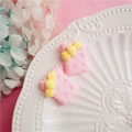 Close-up of pink biscuit-shaped resin charms with yellow bows for DIY craft projects - Pink