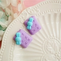 Macro view of purple clay bow cookie charms in a decorative white ceramic tray - Purple
