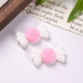Macro shot of two matte resin candy-shaped DIY charms with pink centers and white dots - White + Pink