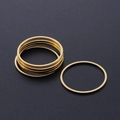 Macro shot of a set of thin gold stainless steel stacking rings on dark grey surface - Round Style (T938) / Gold