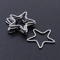 Macro shot of silver polished stainless steel star-shaped DIY jewelry charms on black surface - Silver