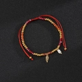 Macro detail of red beaded bohemian bracelet with golden angel wing charm and pearls - Feather