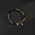 Detail of beaded bracelet with black facets, pearls, and lightning bolt charm on cord - Flash