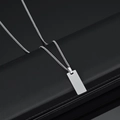 Detailed macro view of a polished stainless steel square dog tag pendant on a Cuban chain - Curb Chain Small Style / Steel