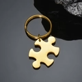Macro detail of a polished gold jigsaw puzzle pendant with reflective metallic finish - Horizontal Puzzle Keychain / Gold