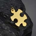 Polished gold puzzle piece pendant in stainless steel displayed on a black natural rock - Vertical Puzzle Pendant / Gold