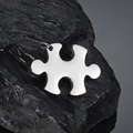 Polished puzzle piece pendant in stainless steel displayed on a black mineral stone base - Horizontal Puzzle Pendant / Steel