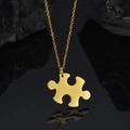 Close-up of a gold-plated puzzle piece pendant with polished S925 finish on black stone - Horizontal Puzzle Necklace / Gold