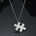 Polished stainless steel puzzle piece pendant with silver chain on black reflective surface - Horizontal Puzzle Necklace / Steel