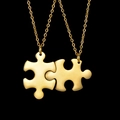 Macro detail of complementary gold puzzle piece pendants with polished stainless steel finish - Puzzle Necklace / Gold