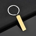 Llavero plateado pulido con colgante rectangular dorado sobre superficie de cuero negro - Dorado